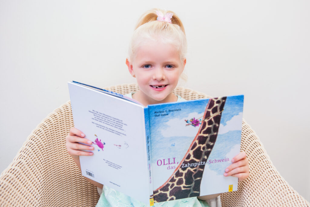 Kind liest aus einem Buch mit einer Giraffe auf der Vorderseite
